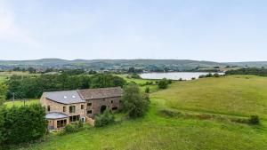 an old stone house on a hill with a lake at Bib Knowl Farm in Littleborough