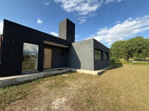 a black house on a field with a grass yard at Casa Marti in Los Reartes