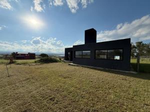 a black house sitting on top of a grass field at Casa Marti in Los Reartes +8 photos