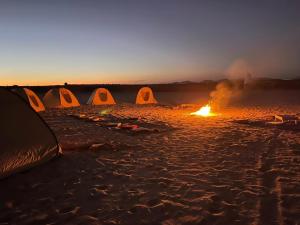 a group of tents on a beach with a fire at مخيم همسات الصحراء in Siwa