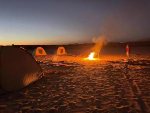 a tent and a bonfire on a beach at night at مخيم همسات الصحراء in Siwa