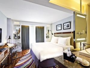 a hotel room with a bed and a desk at The Kuta Beach Heritage Hotel - Managed by Accor in Kuta