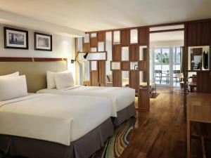a hotel room with two beds and a table at The Kuta Beach Heritage Hotel - Managed by Accor in Kuta +88 photos