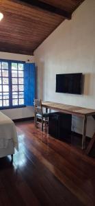 a bedroom with a table and a tv on the wall at Solar Itacaré - Charme e aconchego. in Itacaré