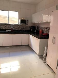 a kitchen with white cabinets and a white tiled floor at Refúgio em Jacumã Conforto, Tranquilidade e Praia in Conde