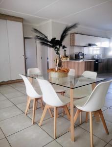 a dining room with a glass table and white chairs at Iris Bnb on Vaal in Vanderbijlpark