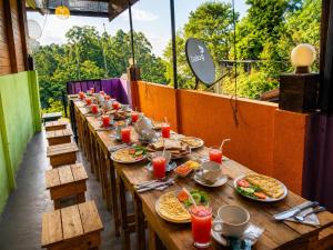 a long wooden table with plates of food on it at Okan Rock Residence in Ella