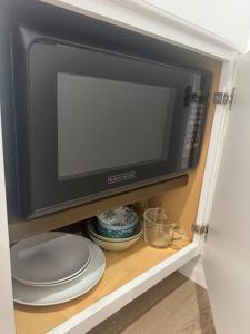 a microwave oven in a cabinet with plates and bowls at Tiny Studio in Orange Garden in Los Angeles