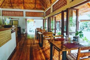 a restaurant with wooden tables and chairs and windows at Balai sa Baibai in Mambajao