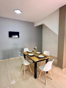 a dining room with a wooden table and white chairs at Serena Suites in Ezeiza