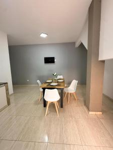 a dining room with a table and white chairs at Serena Suites in Ezeiza +3 photos
