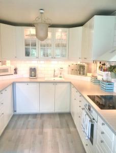 a white kitchen with white cabinets and a sink at Home between flights Gardermoen in Jessheim