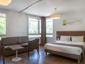 a hotel room with a bed and a couch at Adagio Access Grenoble Université in Saint-Martin-dʼHères