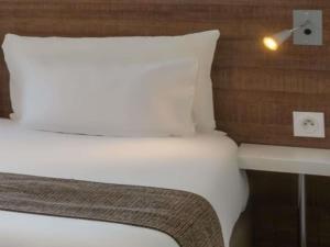 a bed with a white pillow and a table at Adagio Access Grenoble Université in Saint-Martin-dʼHères +73 photos