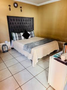 a bedroom with a large bed with a black headboard at Tseleng Guest House in Vosloorus