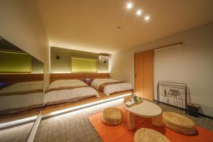 a bedroom with two beds and a table and chairs at 別府の宿 結 -Yui- in Beppu
