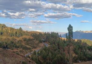 a winding road in the mountains under a cloudy sky at Refugio tierra viva in Cusco