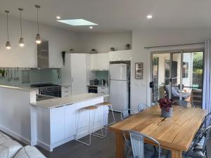a kitchen with white cabinets and a wooden table at Kuruwa in Tathra