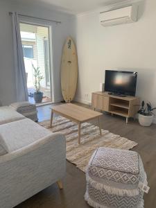 a living room with a table and a surfboard on the wall at Kuruwa in Tathra