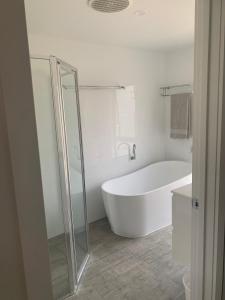 a white bathroom with a tub and a shower at Kuruwa in Tathra +13 photos