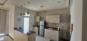 a kitchen with wooden cabinets and a refrigerator at AlSeef 161 in Al Sharqiyah