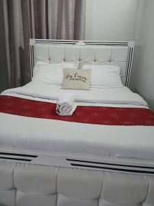 a white bed with a red blanket and a pillow on it at Carley Studio apartment in Thika