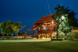 a large wooden building with a lush green yard at Heritage Village Resort in Kampot