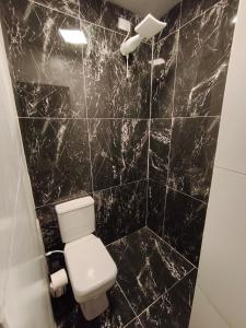 a bathroom with a toilet and a black marble wall at Suíte Completa com Tela de Cinema in Garanhuns +3 photos