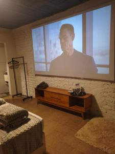 a large screen with a man on a stage at Suíte Completa com Tela de Cinema in Garanhuns
