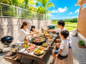 a group of people sitting around a picnic table with food at Maison Haan Motobu in Motobu
