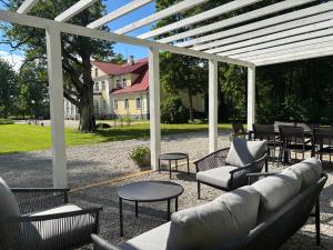 a patio with chairs and tables and a white pergola at Kailes Manor in Aasa