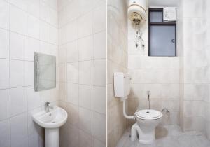 a white bathroom with a toilet and a sink at Shivik stays in Gurgaon