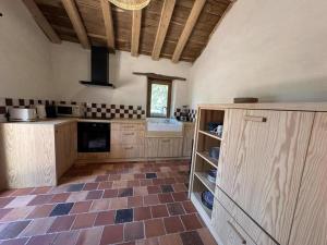 a large kitchen with wooden cabinets and a tile floor at Le résinier in Commensacq +26 photos