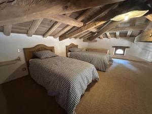 two beds in a room with wooden ceilings at Le résinier in Commensacq