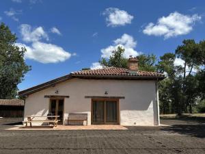a small white house with a bench in front of it at Le résinier in Commensacq