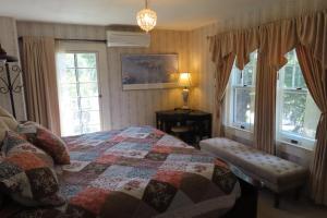 a bedroom with a quilt on a bed and windows at Terraluna Inn in Roseburg