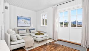 a white living room with a couch and a chair at Astra Village - Waterfront Rorbu Cabins in Lofoten in Kabelvåg