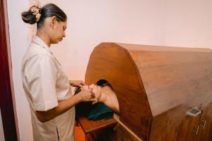 a woman is holding a persons leg in a wooden box at Ayu Ayuruveda Villa in Ittapana