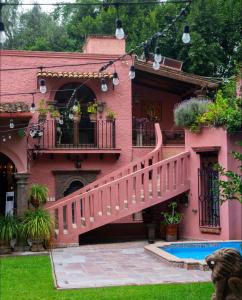 a pink house with a staircase leading to a swimming pool at Tres Fuentes Hotel Boutique in San Miguel de Allende