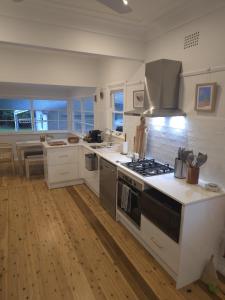 a kitchen with white cabinets and a stove top oven at The Seaside Haven Umina in Umina