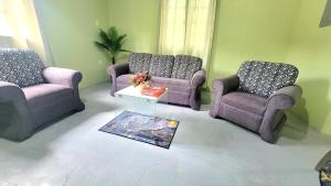 ein Wohnzimmer mit drei Stühlen und einem Tisch in der Unterkunft Tranquil Escape in Arima