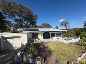 a small white house with a grass yard at Cliff Place in Tathra