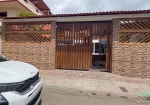 a house with a wooden gate and a car parked in front at Casa playa crucita in Crucita