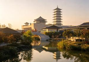 a bridge over a river with a chinese building at Bristoria Hotel Yangzhou in Yangzhou