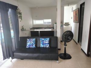 a living room with a black couch and a fan at Oasis Santafe in Santa Fe de Antioquia +3 photos