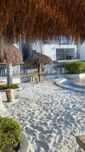 a beach with some straw umbrellas on the sand at Oasis Santafe in Santa Fe de Antioquia