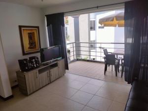 a living room with a television and a balcony at Oasis Santafe in Santa Fe de Antioquia