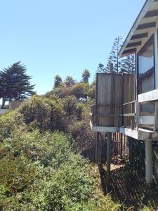a house with a bench next to a hill at Cabañas mirasol in Algarrobo