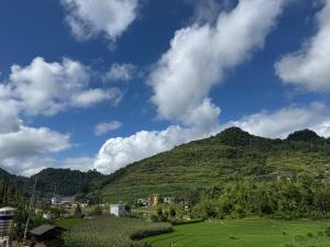 a green hill with a town on top of it at Lũng Cú H'Mông Homestay in Loung Co