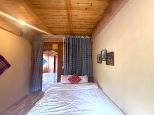 a bed in a room with a wooden ceiling at Lũng Cú H'Mông Homestay in Loung Co